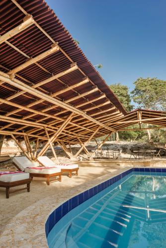 a swimming pool with awning and chairs and a swimming pool at Castillete Hotel & Beach Club in Tierra Bomba