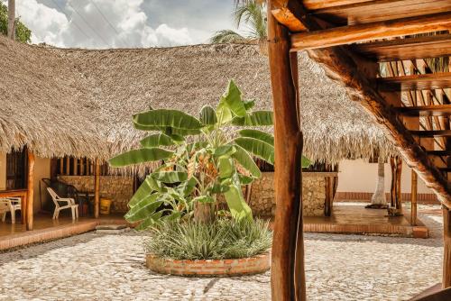 a patio with a palm tree and a thatch roof at Castillete Hotel & Beach Club in Tierra Bomba