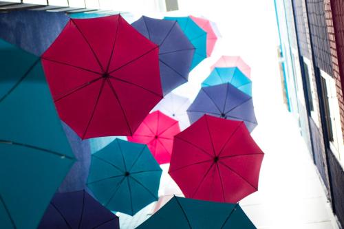 a bunch of colorful umbrellas hanging from a building at Apartosuites Jardines de Sabatini in Madrid