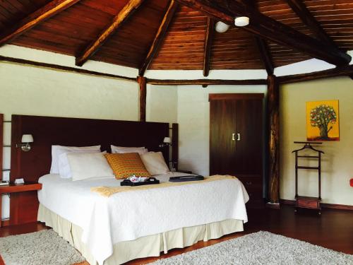 a bedroom with a large bed in a room with wooden ceilings at Casa d'Campo Tababela Hotel Boutique in Tababela