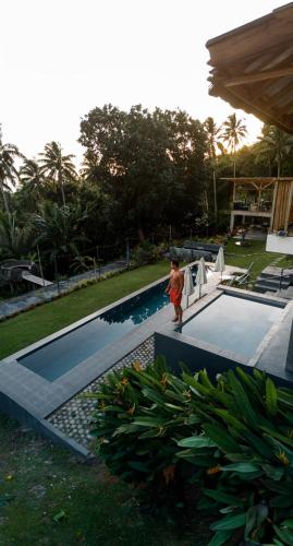 a man is standing next to a swimming pool at Bintana sa Paraiso Binunsaran in Mambajao