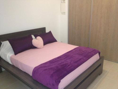 un lit avec une couverture violette et des oreillers violets dans l'établissement Les Lones avec jardin, à Six-Fours-les-Plages