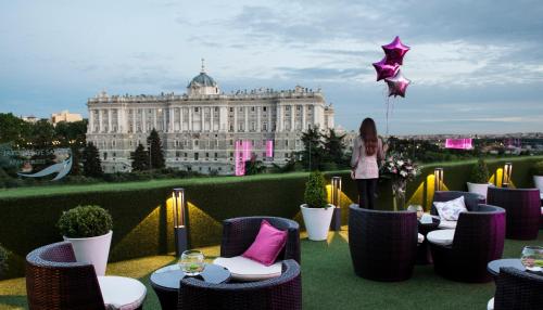 a woman standing on the roof of a building at Apartosuites Jardines de Sabatini in Madrid