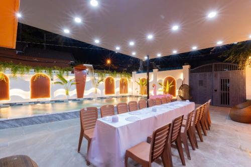 a long table and chairs in a room with a pool at Sun Villa 168 - 7 Phòng Ngủ - Gần Biển Bãi Sau in Vung Tau