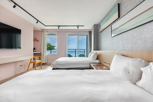 a bedroom with two beds and a large window at Jhai Wu in Kenting