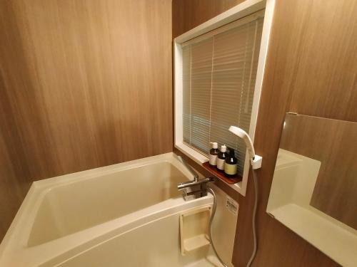 a bathroom with a bath tub and a window at HANOOTO Kitakarauizawa in Tsumagoi