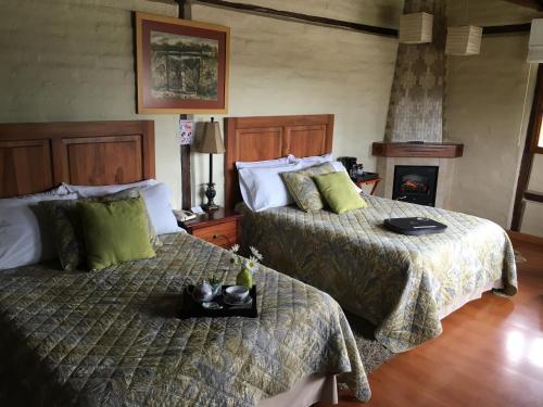 a bedroom with two beds and a fireplace at Casa d'Campo Tababela Hotel Boutique in Tababela