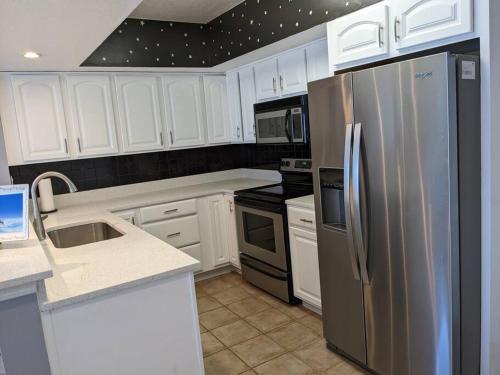 a kitchen with white cabinets and a stainless steel refrigerator at Oceanfront 2Br-2B in Satellite Beach - Ocean Views in Satellite Beach