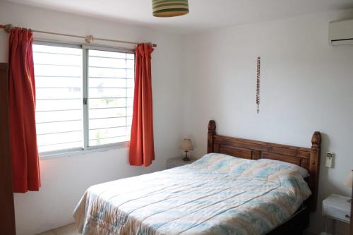 a bedroom with a bed and a window with red curtains at Etulia in Cuchilla Alta