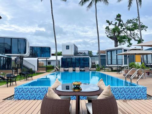 a pool with a table and chairs next to a building at Space House Hotel Phuket in Rawai Beach
