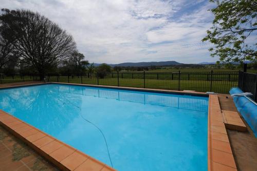 a large blue swimming pool with a fence at Redbank Estate - Luxury in Scone in Scone