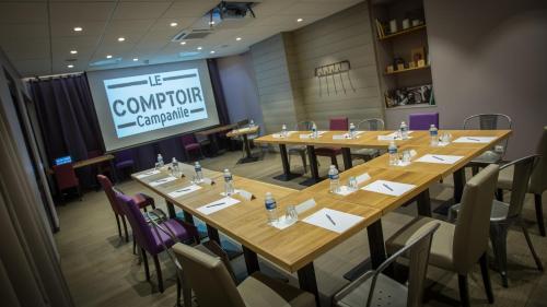 a conference room with wooden tables and chairs and a screen at Campanile Dijon Centre - Gare in Dijon