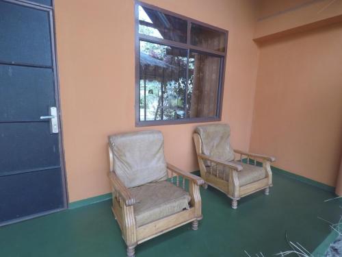 two chairs sitting in a room with a window at East Homestay in Boma la Ngombe