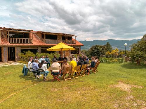 a group of people sitting at a table under a yellow umbrella at Cabañas la odisea in Subachoque