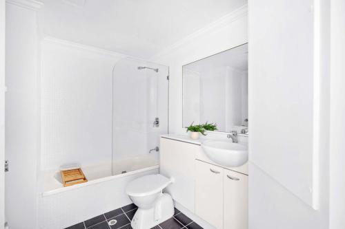 a white bathroom with a toilet and a sink at Central Chic Stay in Perth