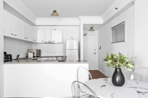 a white kitchen with a table and a vase with flowers at Central Chic Stay in Perth