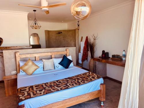 Schlafzimmer mit einem Bett mit blauer Bettwäsche und Kissen in der Unterkunft Zanzi Soul Luxury Boutique Hotel in Jambiani