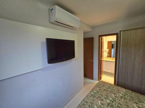 a room with a tv on the wall and a bed at Apartamentos em Rio Quente com maravilhosa área de lazer e excelente localização in Rio Quente