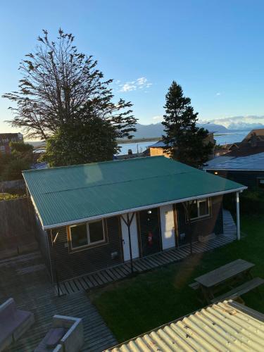a small house with a green roof on a deck at Hostal Amerindia in Puerto Natales
