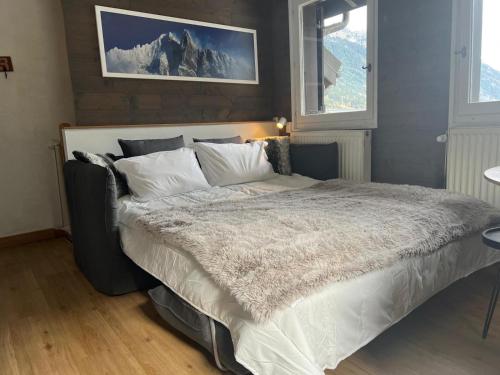 une chambre avec un grand lit avec des draps blancs dans l'établissement Chamonix Charmant duplex 4 personnes et un enfant, à Chamonix-Mont-Blanc