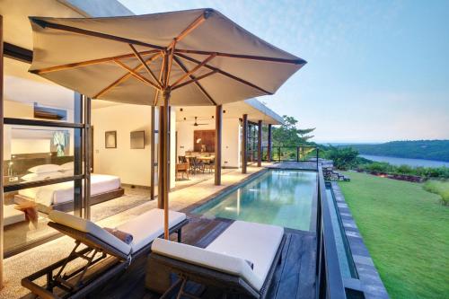 an outdoor patio with a pool and an umbrella at MAUA Nusa Penida Bali in Nusa Penida