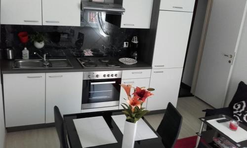 a kitchen with white cabinets and a table with a vase of flowers at Apartments Paris in Umag