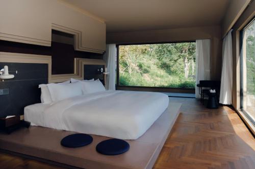 a bedroom with a large white bed and a large window at MUUA Hotel in Wushan