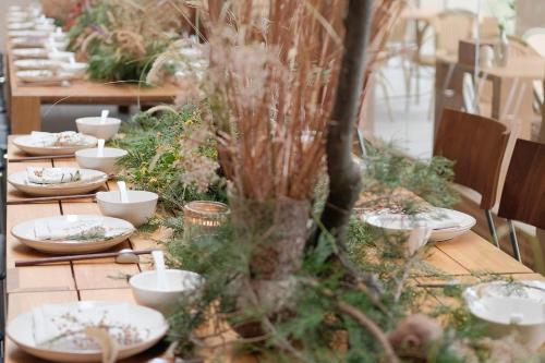 a long table with white dishes and plants on it at MUUA Hotel in Wushan