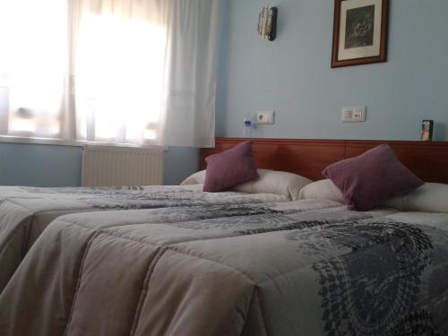 a bedroom with two beds with pillows and a window at Hostal Campus in Burgos