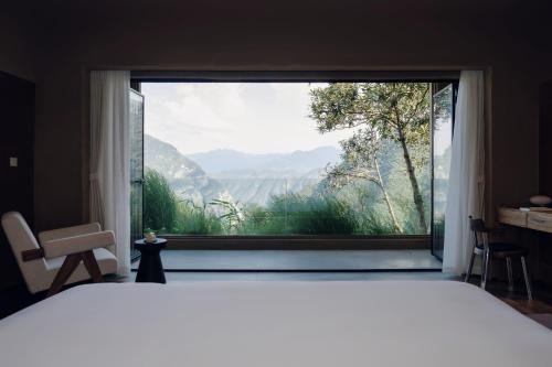 a bedroom with a large window with a mountain view at MUUA Hotel in Wushan