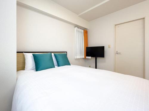 een slaapkamer met een groot wit bed met blauwe kussens bij Luce Takanawa in Tokyo