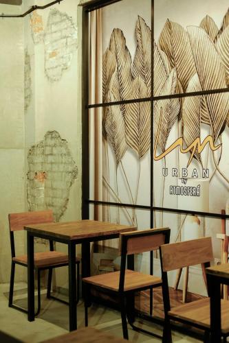 a table and chairs in front of a wall with a picture at Lyn Urban by Atmosfera in Jepara