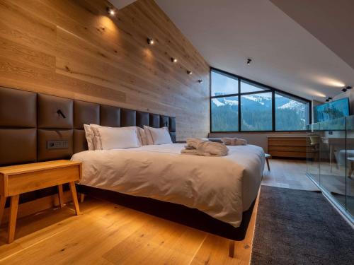 a bedroom with a large bed and a large window at Swissôtel Damian Jasna in Demanovska Dolina