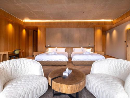 a room with two beds and a table and chairs at Swissôtel Damian Jasna in Demanovska Dolina