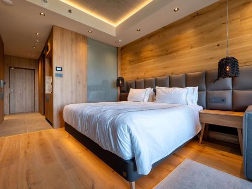 a bedroom with a large bed and a wooden wall at Swissôtel Damian Jasna in Demanovska Dolina