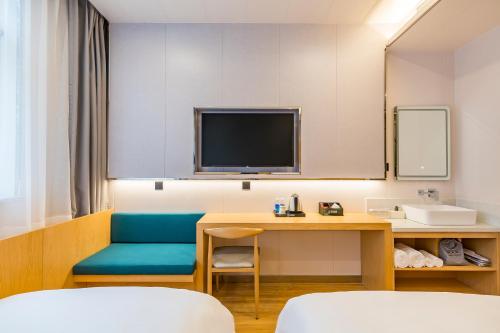 a room with a desk and a tv and a chair at Dequan Luxury Hotel Communication University of China Branch Coffee, fruits, snacks, a gym and a laundry room are provided for free in the lobby in Beijing
