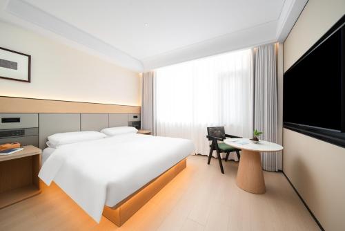 a hotel room with a bed and a table and a tv at Constellation XingSu Boutique Hotel in Huangshan