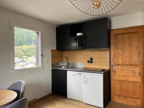 une cuisine avec des placards noirs et blancs et une fenêtre dans l'établissement Chamonix Charmant duplex 4 personnes et un enfant, à Chamonix-Mont-Blanc