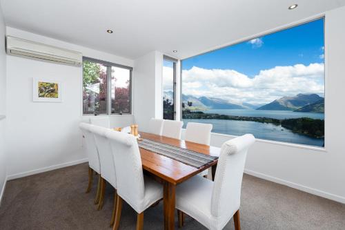 a dining room with a table and chairs and a large window at Panoramic Lake Wakatipu Escape in Queenstown