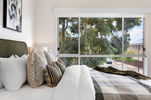a bedroom with a bed with pillows and a large window at Mawson Lakes Retreat - 3BR, Wifi, Parking in Mawson Lakes