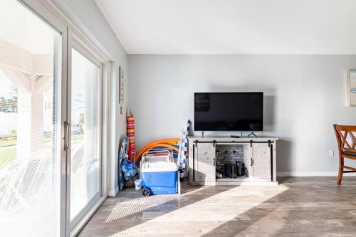 a living room with a flat screen tv next to a window at Ocean Front by Cocoa Beach Pier in Cocoa Beach