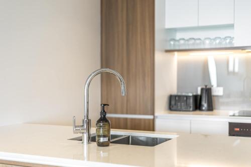 a bottle of wine is sitting on a kitchen sink at Urban Retreat 2 Bd Apt WiFi AC Parking in Auckland