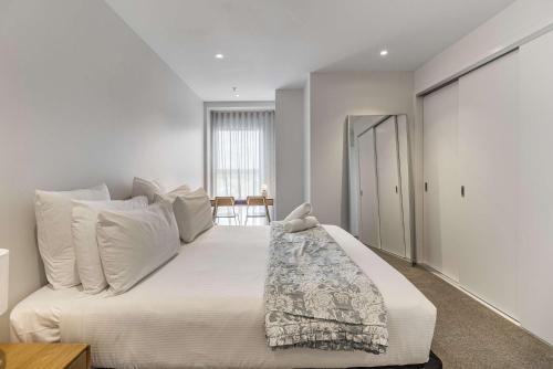 a bedroom with a large white bed with white pillows at Urban Retreat 2 Bd Apt WiFi AC Parking in Auckland