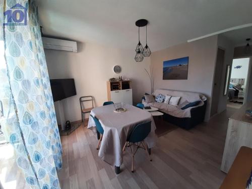 un salon avec une table et un canapé dans l'établissement Valras-Plage: Apt 4 pers, clim, parking privé, proche plage - FR-1-781-56, à Valras-Plage