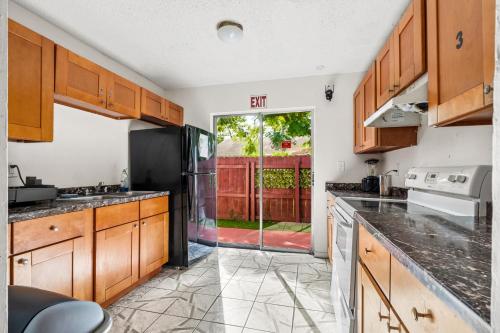 a kitchen with wooden cabinets and a door to a yard at Crocodhouse early check in eight years hosting in Fort Lauderdale