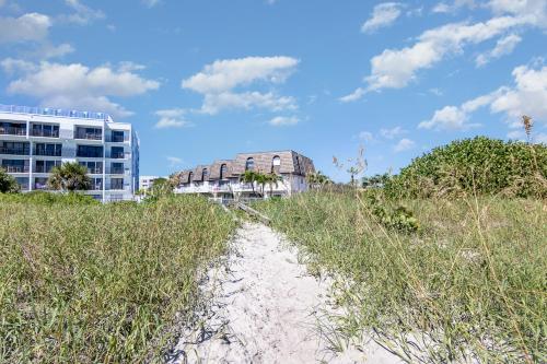 a sandy path through a field of grass next to a building at Ocean Front by Cocoa Beach Pier in Cocoa Beach