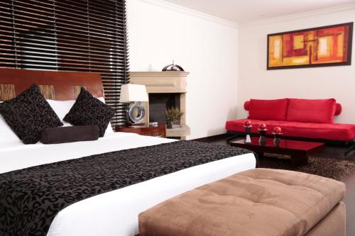 a bedroom with a large bed and a red couch at Hotel Suites 108 in Bogotá