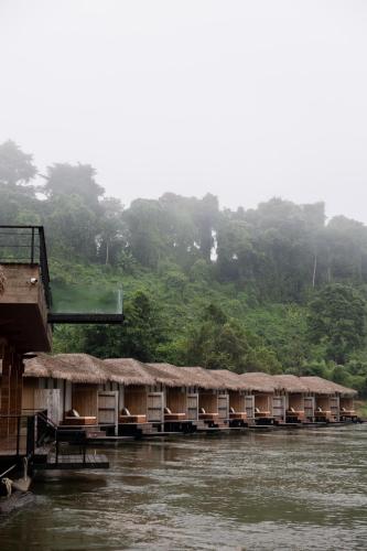 a row of huts on the side of a river at Cherlynn Resort in Ban Gaeng Cho