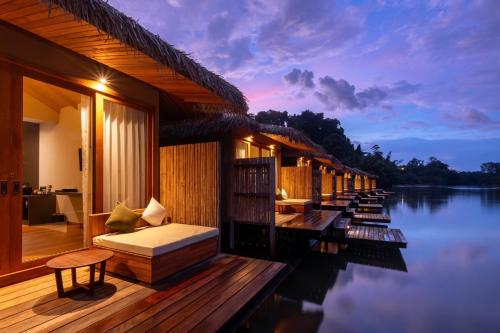 a room with a bed on a deck next to water at Cherlynn Resort in Ban Gaeng Cho