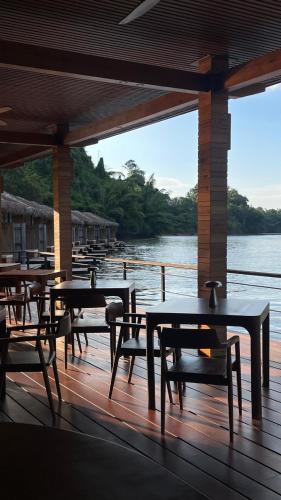 a group of tables and chairs on a deck next to the water at Cherlynn Resort in Ban Gaeng Cho